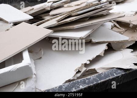 In der Nähe einer Baustelle steht ein riesiger überladener Müllcontainer, der mit Bauabfällen, Trockenbauteilen und anderen Schutt überfüllt ist. Der Behälter i Stockfoto