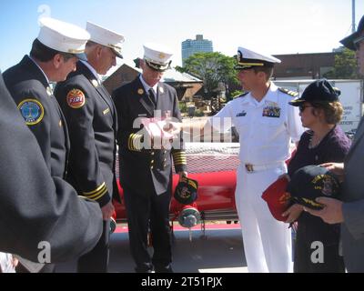 1007262148B-001 BROOKLYN, N.Y. (26. Juli 2010) Commander. Curt Jones, Befehlshaber des Amphibientransportschiffes USS New York (LPD 21), überreicht eine Gedenktafel an Chief Edward Kilduff, Chef der New York Fire Department (FDNY), an Bord des FDNY Marine Fireboat 343 in Brooklyn Navy Yard als Chief James Dalton, links, FDNY Marine Operations; Chief William Sellig, FDNY Head of Special Operations, und pensionierter Navy Captain Sally McElwreath, rechts, Direktor des USS New York Commissioning Committee, sehen Sie zu. New York wurde mit 7,5 Tonnen World Trade Center Stahl in ihrem Bug gebaut, während FDNY Stockfoto