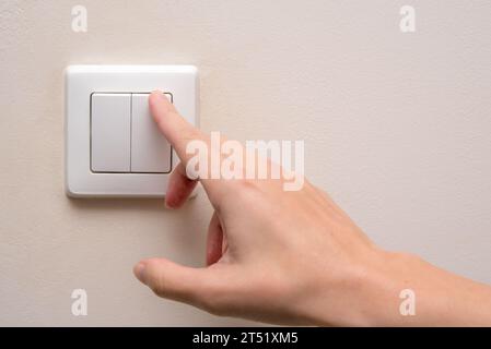 Frau schaltet einen Lichtschalter in einem Wohnzimmer an Stockfoto