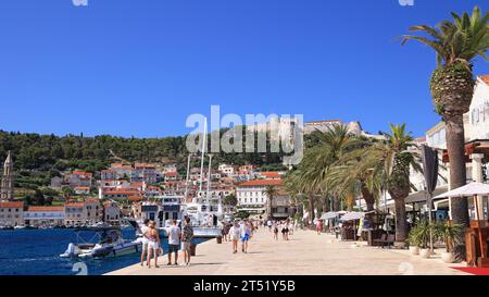 Touristen genießen Hvar, einschließlich Hafen und Festung auf dem Hügel, Kroatien Stockfoto