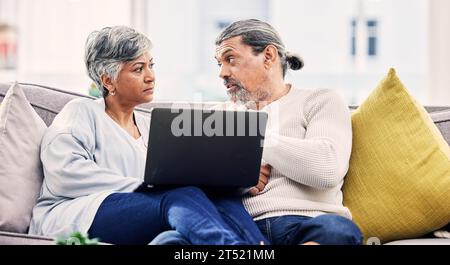 Seniorenpaar, Laptop und ernsthafte Diskussion auf Sofa für Finanzplanung, Budget oder Schulden zu Hause. Ältere Männer und Frauen, die mit dem Computer sprechen Stockfoto