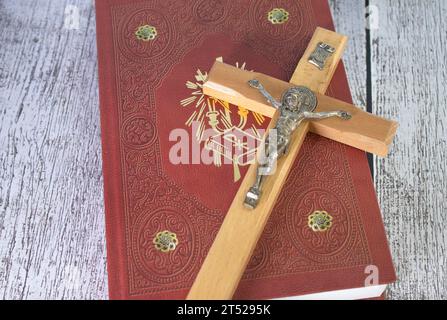 Das hölzerne Kreuz über geöffneter Bibel auf Holztisch mit Fensterlicht, Vintage-Ton. Stockfoto