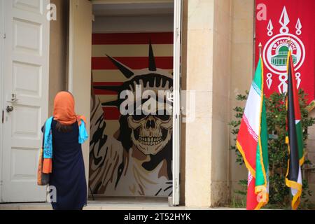 Teheran, Iran. November 2023. Eine ausländische Touristin steht vor einem Anti-US-Schild, während sie das Gebäude besucht, das früher die Botschaft der Vereinigten Staaten in Teheran beherbergte, heute das Museum der Spione genannt. Die Botschaft der Vereinigten Staaten in Teheran war die diplomatische Mission der Vereinigten Staaten im Iran. Die US-Botschaft in Teheran ist seit dem 4. November 1979 geschlossen, als iranische Militante sie während der Geiselkrise im Iran ergriffen haben. Die Beschlagnahme der Botschaft führte zur Inhaftierung von 52 amerikanischen Diplomaten und Bürgern für 444 Tage. Seit der Schließung der Botschaft, diplomatischer Abgeordneter Stockfoto