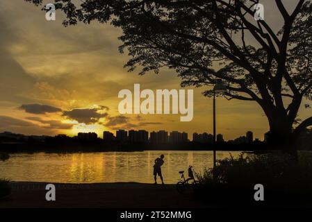 Ein Mann, der am Rande des Jurong Lake im Westen Singapurs Sport macht. Im Hintergrund befinden sich Gebäude in Jurong East. Stockfoto