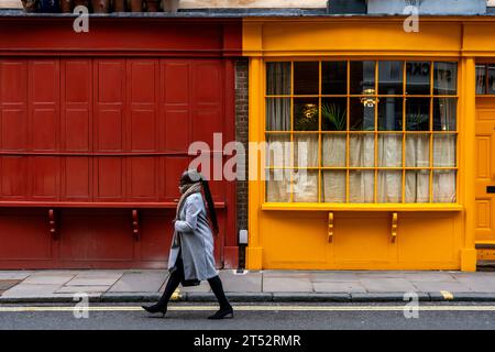 Eine Frau läuft an einem farbenfrohen Anwesen in der Bermondsey Street, Bermondsey, London, Großbritannien, vorbei Stockfoto