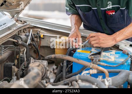 Ein Mechaniker zieht die Batterieanschlüsse mit einem Schraubenschlüssel fest, nachdem die Ladung voll ist. Stockfoto