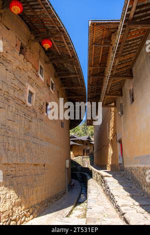 Der Weg zwischen zwei Tulou-Schlammgebäuden mit blauem Himmel, Fujian, China. Vertikales Bild Stockfoto