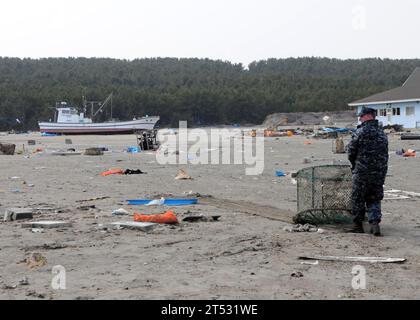 110314MU720-012 MISAWA, Japan (14. März 2011) Ein Seemann, der der Naval Air Facility Misawa (NAFM) zugewiesen ist, transportiert während eines Aufräumens im Misawa Fishing Port Trümmer. Mehr als 90 Seeleute der Naval Air Facility Misawa meldeten sich freiwillig, um Mitarbeitern und Mitgliedern der Gemeinde Misawa bei der Reinigung nach einem Erdbeben und Tsunami zu helfen. Stockfoto