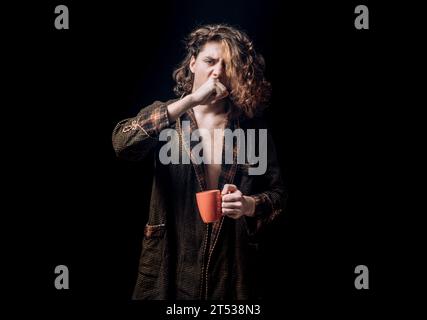 Mans hält eine Tasse Kaffee und Gähnen. Morgentee. Gähngesicht. Mann mit Teetasse. Hipster-Mann gähnt mit einer Tasse Kaffee. Bärtiger Mann, der Gähnen hält Stockfoto