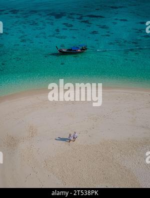 Ein paar Männer und Frauen auf einer weißen Sandbank im Ozean von Koh Lipe Island im Süden Thailands. Stockfoto