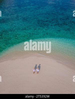 Ein paar Männer und Frauen an einer weißen Sandbank im Ozean von Koh Lipe Island im Süden Thailands an einem sonnigen Tag Stockfoto