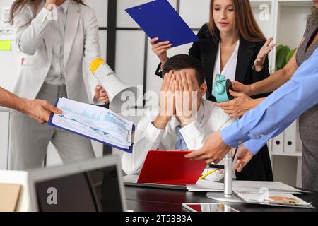 Reifer Geschäftsmann, der unter lauten Kollegen im Büro leidet Stockfoto