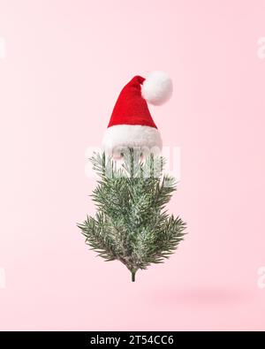 Weihnachtsbaum im Weihnachtsmann-Hut auf rosa Hintergrund in minimalem Stil. Stockfoto