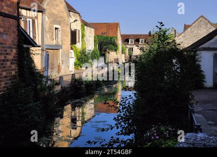 Chablis: Ehemalige Mühle (heute Hotel) und andere Gebäude mit Spiegelreflexen im Fluss Serein kurz nach Sonnenaufgang in Chablis, Burgund, Frankreich Stockfoto