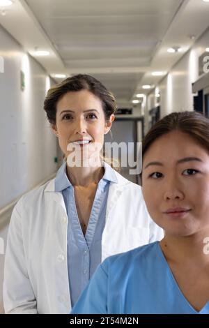 Zwei glückliche verschiedene Ärztinnen stehen im Krankenhauskorridor Stockfoto