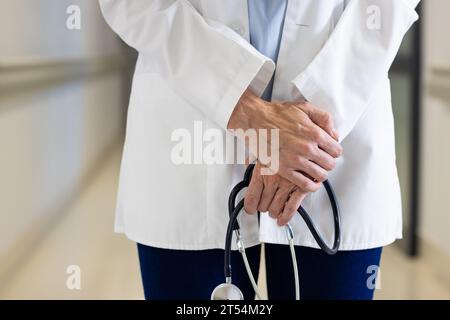 Mittelteil einer kaukasischen Ärztin mit Stethoskop im Krankenhauskorridor Stockfoto