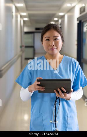 Porträt einer lächelnden asiatischen Ärztin mit Tablette im Krankenhausflur Stockfoto