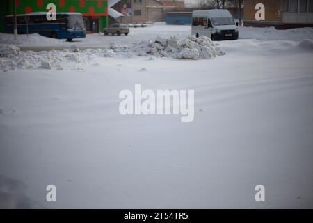 Das Auto steht im Winter auf dem Parkplatz. Das Auto steht im Schnee. Winterparkplätze in der Stadt. Viel Schnee auf der Straße und auf den Transportmitteln. Stockfoto