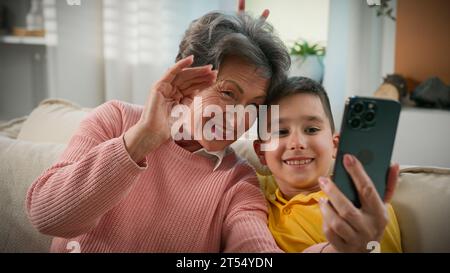 Kaukasische Großmutter und Enkel zusammen auf der Heimcouch fotografierten Selfie auf Handy-Narr um lustige Familie zwei Generationen Großmutter machen Stockfoto