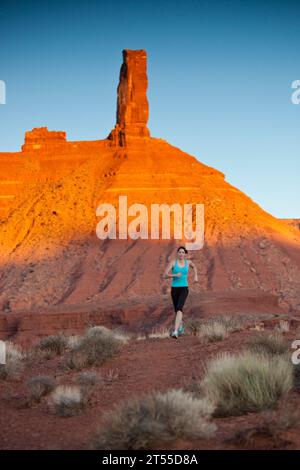 Frau, die mit Castleton Tower im Hintergrund läuft, Castle Valley, Utah. Stockfoto