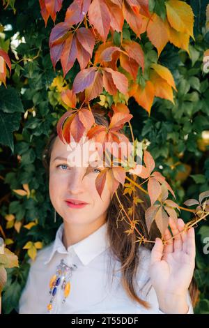 Junge Frau, die in einem Herbstpark zwischen rotem Laub in Prag spaziert Stockfoto