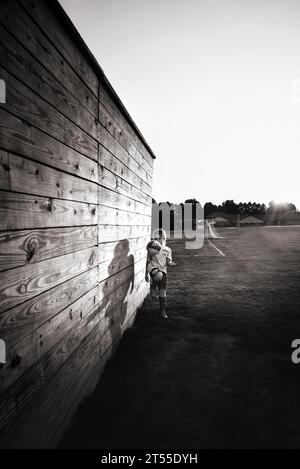 Ein junges Mädchen, das bei Sonnenuntergang Fußball auf dem Feld dribbelt Stockfoto