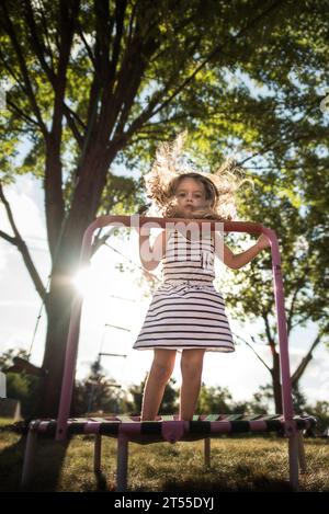 Schönes kleines Mädchen, das im Hinterhof auf Trampolin springt Stockfoto