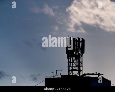 Silhouette des Telekommunikationsturms mit Antennen für Mikrowellenfelder, Fernsendereinheiten, Funktechnologie, GSM, 5G, Lichtwellenleiter auf dem Dach von b Stockfoto