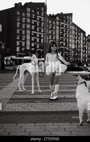 Mädchen mit weißem Hund auf einem Spaziergang in der Stadt. Stockfoto