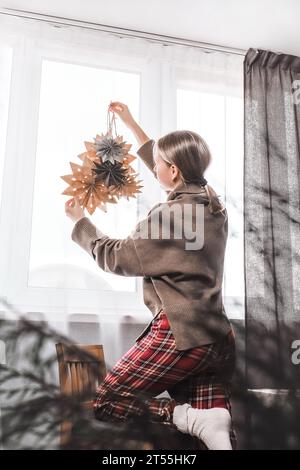 Frau, die Haus und Fenster zu weihnachten mit Papiersteinen dekoriert Stockfoto