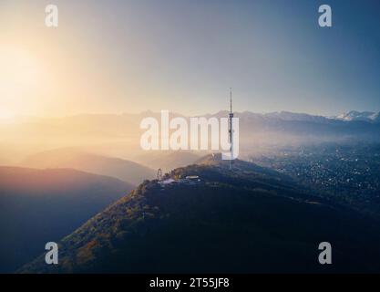 Luftdrohnenaufnahme von Symbol Almaty City hoher Fernsehturm und Park auf dem Koktobe Hügel vor Schnee Berge bei Sonnenaufgang in Kasachstan Stockfoto