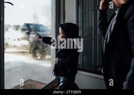 Seitenansicht eines kleinen Jungen, der Winterkleidung trägt und auf frostigem Boden steht Stockfoto