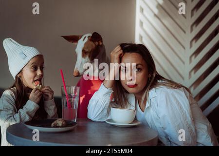 Mutter mit Tochter und Hund in einem Café. Haustiere sind willkommen. Stockfoto