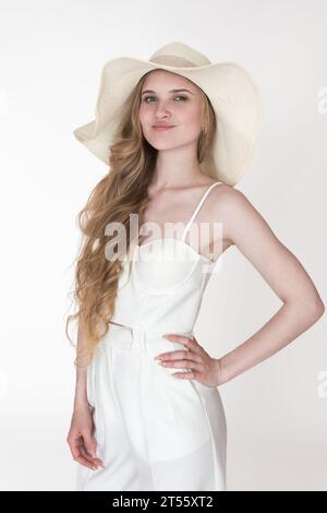 Porträt eines europäischen Models in neuen Kleidern, um Strohhut, weißes Korsett und Hose zu verkleiden. Kopfschuss weiblich Stockfoto