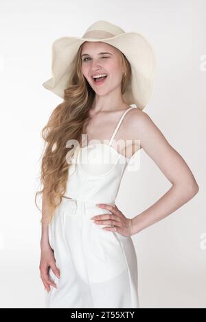 Porträt einer blonden Frau lächelt spielerisch von Ohr zu Ohr mit einem geschlossenen Auge und blinkender Kamera. Gesichtsausdruck der glücklichen jungen Frau Stockfoto