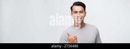 Junger gutaussehender asiatischer Mann über weißem Banner Hintergrund, der mit der Hand glückliche Daumen nach oben drückt. Stockfoto