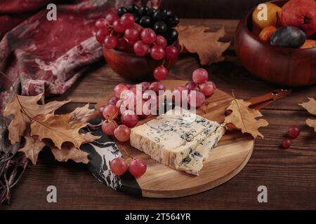Käseplatte mit Herbstfrüchten und trockenen Blättern Stockfoto