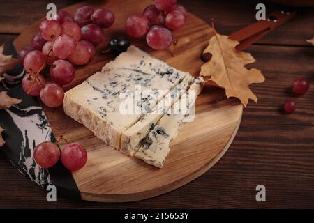 Käseplatte mit Herbstfrüchten und trockenen Blättern Stockfoto