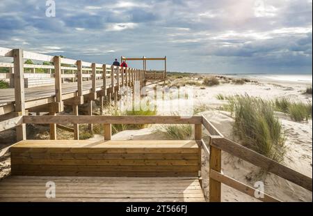 Besucher spazieren über eine hölzerne Fußgängerbrücke am Strand Monte Gordo, Vila Real de Santo Antonio, Portugal Stockfoto