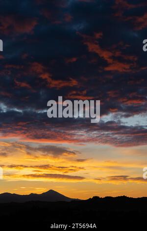 Atemberaubender Sonnenaufgang mit wunderschönen Orange-, Rosa-, Lila- und Blautönen mit der Silhouette einer Bergkette. Hintergrundbild, natürlicher Hintergrund Stockfoto