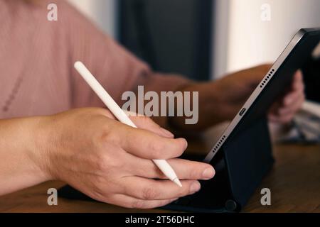 Unerkennbare Frauenhand mit einem Grafiktablett-Computer mit Stift-Stift in einem Café. Zugeschnittene Aufnahme einer Frau, die auf einem digitalen Touchscreen arbeitet DE Stockfoto