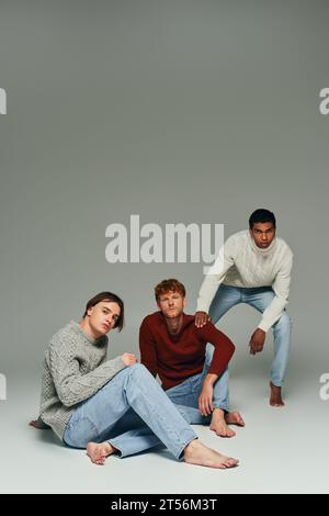 Interrassische männliche Models in pulsierenden Pullover posieren auf grauem Hintergrund, Hand an Schulter, Männer Power Stockfoto