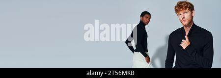 Stilvolle rothaarige und afroamerikanische Männer in schwarzen Rollkragenbändern, die vor grauem Hintergrund posieren, Banner Stockfoto