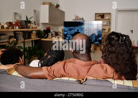 Schwarze Familie, die eine aufgezeichnete Rede von Martin Luther King Jr im fernsehen ansieht, Blick von hinten Stockfoto
