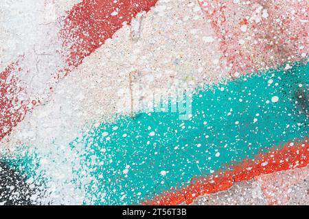 Makroaufnahme einer Wand mit bunten Sprühfarben und Spritzern. Weiß, Rot und Türkis. Abstrakter strukturierter und spritzender Graffiti-Hintergrund Stockfoto