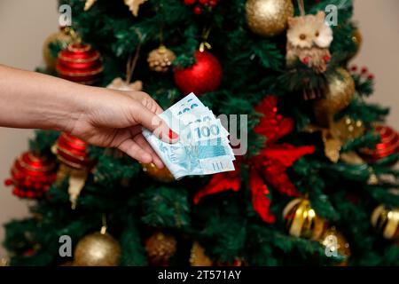Mehrere hundert echte Rechnungen - Geld aus Brasilien in einer Frauenhand mit roten Nägeln - Zahlung für Weihnachten und Neujahr Stockfoto
