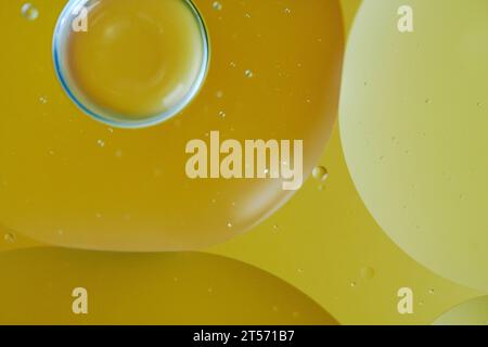 Ölblasen von oben fallen auf das Wasser mit farbenfrohem Hintergrund, Makrofotografie-Konzept Stockfoto