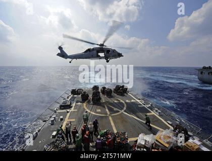 US Navy ein MH-60R Sea Hawk Helikopter bringt Vorräte zum Flugdeck der Arleigh Burke-Klasse Lenkrakete destroyer.jpg Stockfoto
