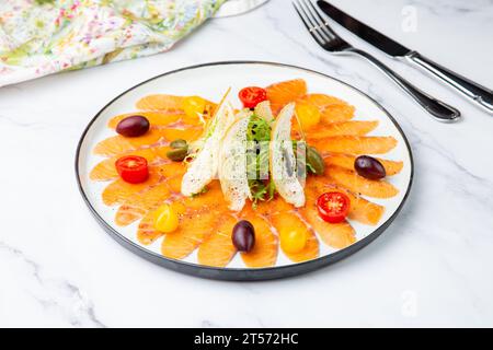 In Scheiben geschnittene rote Fischscheiben mit Kräutern, Kirschtomaten und Weißbrotcroutons Stockfoto