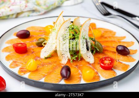 In Scheiben geschnittene rote Fischscheiben mit Kräutern, Kirschtomaten und Weißbrotcroutons Stockfoto